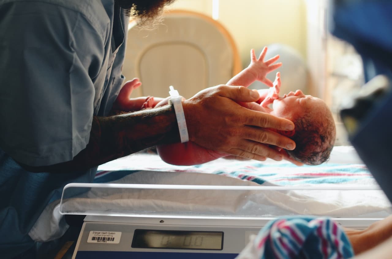 Nurse weighing a newborn baby